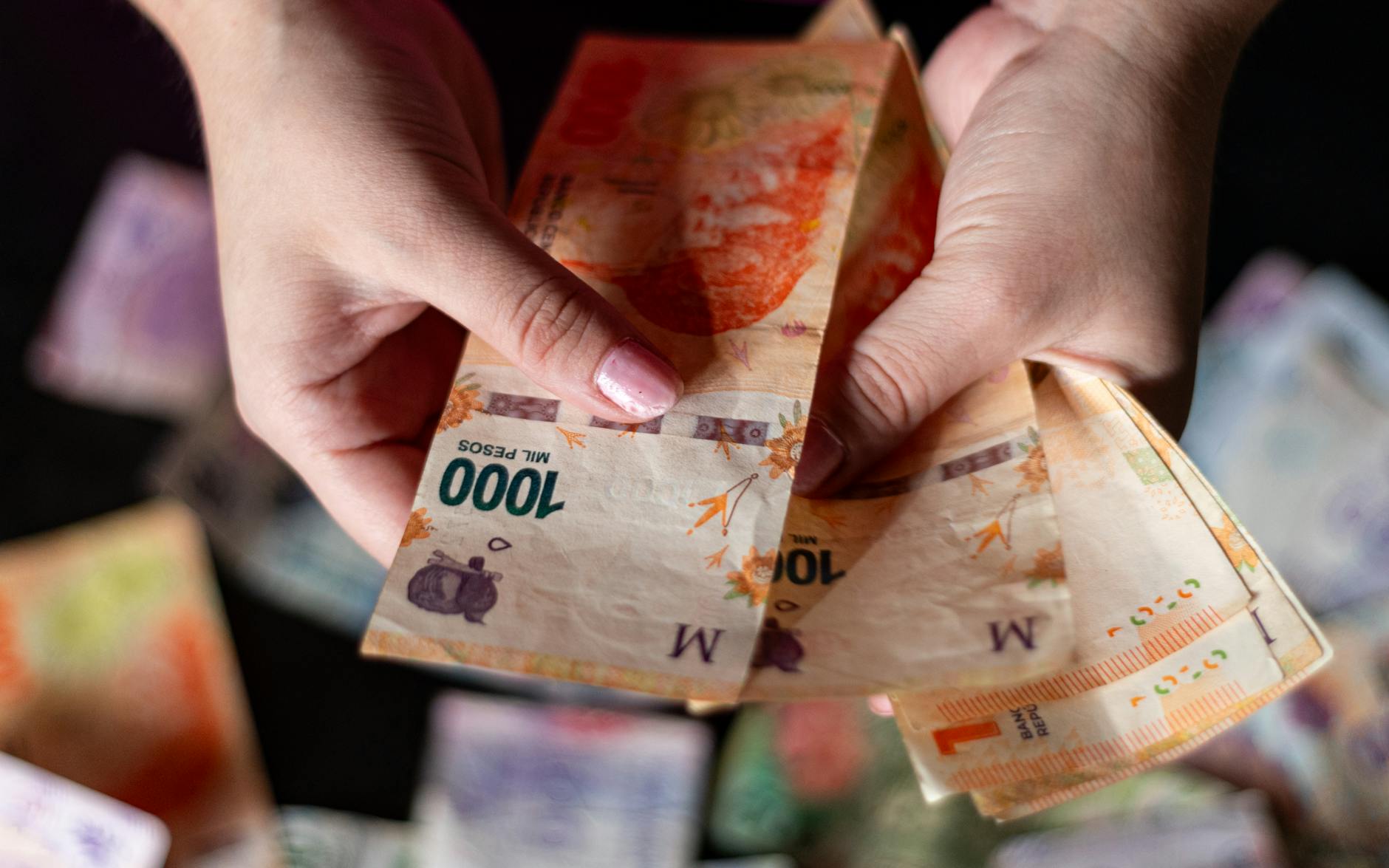 Hands holding Argentine peso banknotes